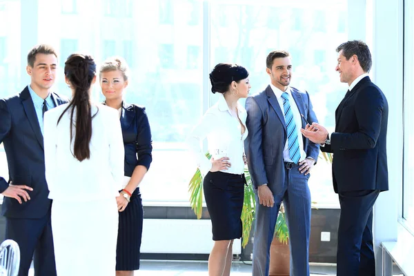 Grupp av affärsmän talar, stående i lobbyn på kontoret. — Stockfoto