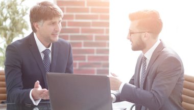 Ofiste bir dizüstü bilgisayar üzerinde çalışan iki iş adamları