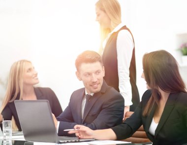 yeni bilgi tartışırken, ofis içinde açık belgili tanımlık laptop önünde duran iş takım.