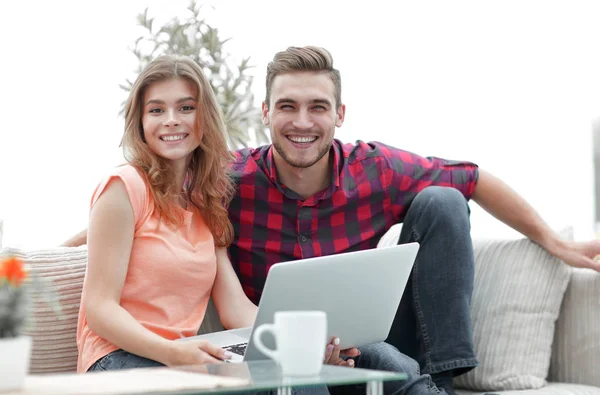 Pareja joven .working en el ordenador portátil sentado en el sofá — Foto de Stock