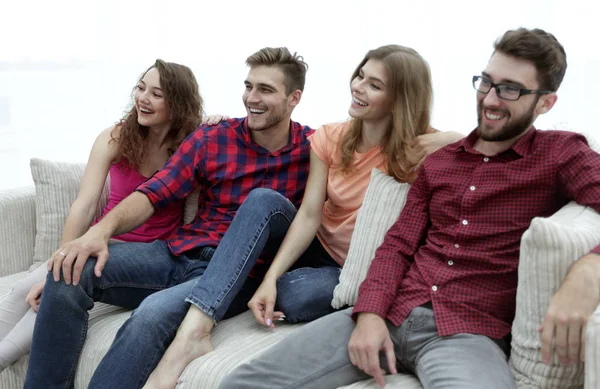 Группа улыбающихся молодых людей, сидящих на диване — стоковое фото