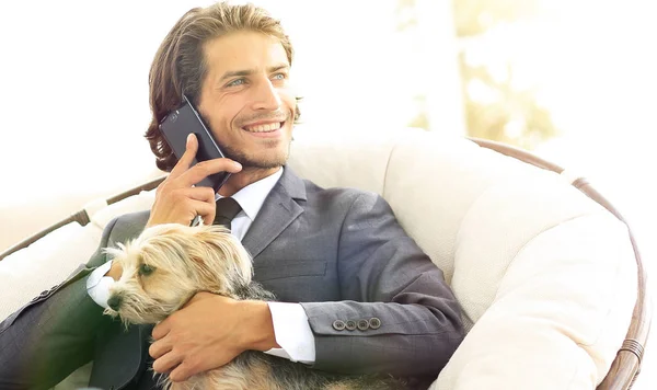 successful businessman holds his dog and pet and talks on the smartphone