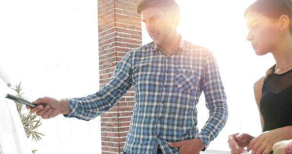 Šťastný muž v kostkované košili, stojící v kanceláři poblíž flipchart — Stock fotografie