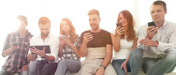 Junge Leute in lässiger Kleidung mit Gadgets — Stockfoto