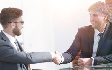 Toplantı sırasında iki iş arkadaşı el sıkışıyor.