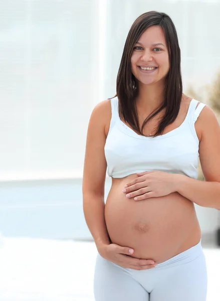 Hafif arka planda genç hamile bir kadının portresi. — Stok fotoğraf