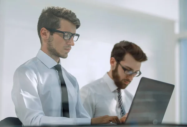 Zwei seriöse Mitarbeiter arbeiten im Büro an Laptops. — Stockfoto