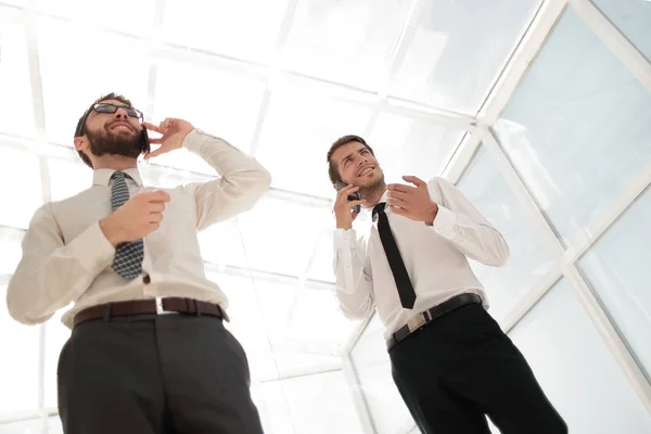 Bottom view.two uomini d'affari di successo parlando sui loro smartphone . — Foto Stock