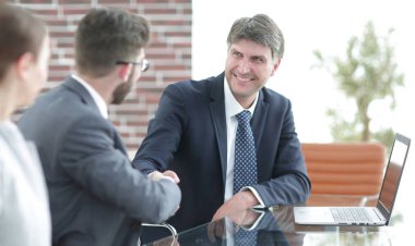 Masadaki iş adamlarının el sıkışması.