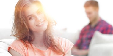 Gülümseyen genç bir kadın büyük rahat bir sandalyede oturuyor.