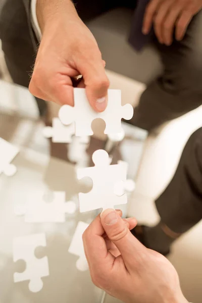 Close up.pieces of the puzzle in the hands of business partners — Stock Photo, Image