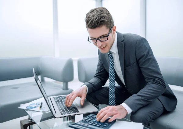 Jeune homme d'affaires utilisant calculatrice et ordinateur portable — Photo