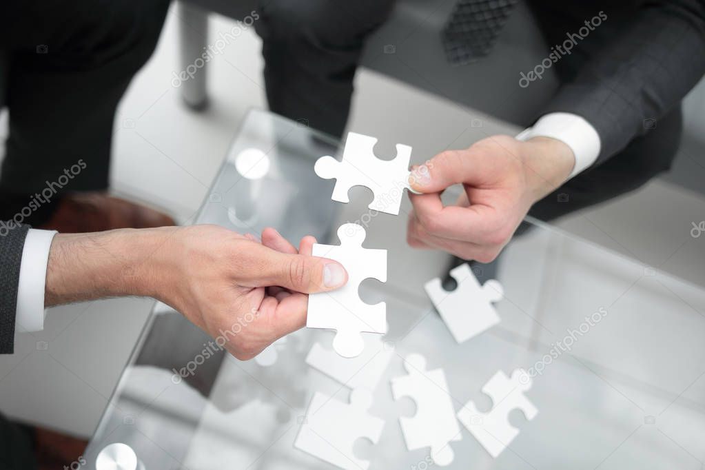 close up.business partners hold the puzzle pieces