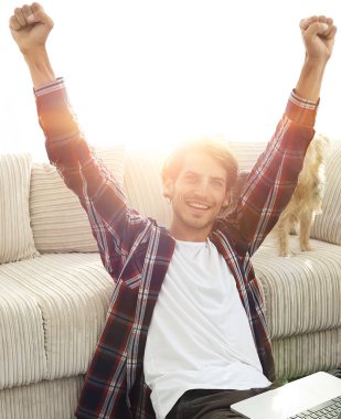 mutlu genç adam köpeğiyle oturma odasında exults