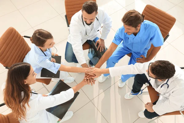 Medisch personeel handen geklemd samen zitten aan een bureau — Stockfoto