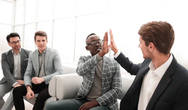 Collega's geven elkaar een high five zittend op kantoor lobby. — Stockfoto