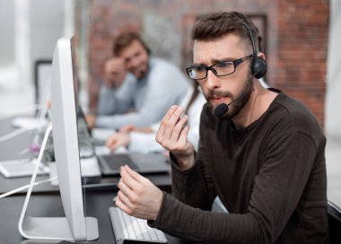 adam bir parlak ofisindeki bilgisayarlar tarafından oturan kulaklık ile