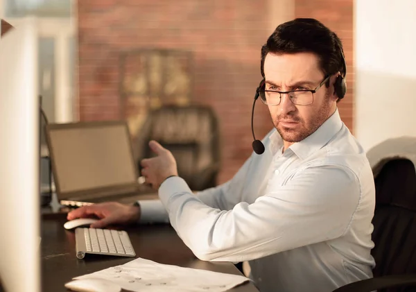 Nära up.businessman med ett headset som sitter vid sitt skrivbord — Stockfoto