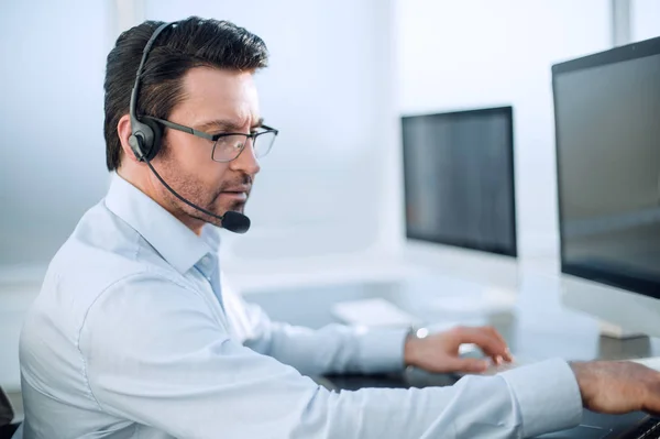 Close up.businessman com um fone de ouvido funciona em um escritório moderno — Fotografia de Stock