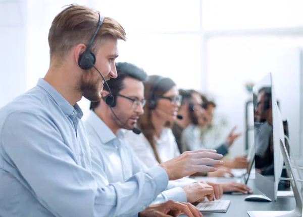 Homem bonito com um fone de ouvido trabalhando em um call center — Fotografia de Stock