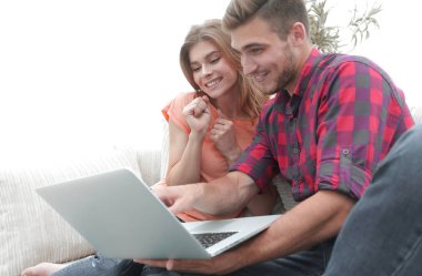 Genç çift kanepede oturan dizüstü bilgisayar ile gülümseyen