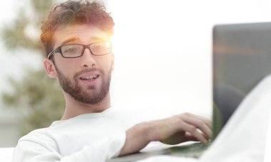 gülümseyen adam yatakta yatarken dizüstü bilgisayar kullanarak