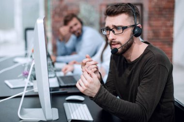 adam bir parlak ofisindeki bilgisayarlar tarafından oturan kulaklık ile