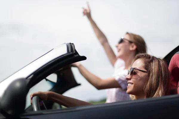 Stäng up.two unga kvinnor reser i en cabriolet bil — Stockfoto