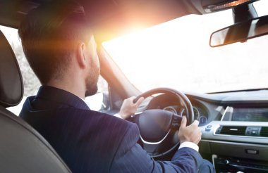 işadamı direksiyonda arabasında oturur ve yola görünüyor