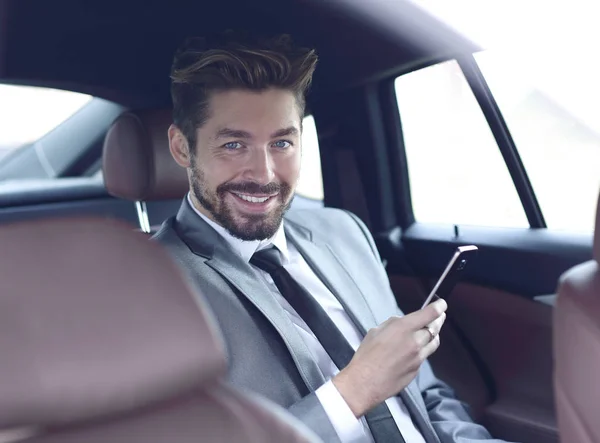 Hombre de negocios sonriendo mientras está sentado en el asiento trasero en el coche — Foto de Stock