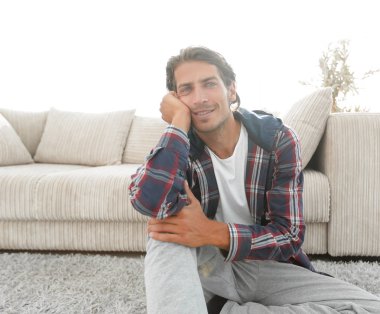 Kendine güvenen adam rahat bir oturma odasında halı üzerinde oturan.