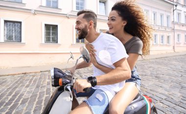 mutlu genç bir çift bir scooter üzerinde eğleniyor
