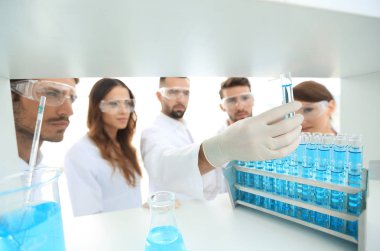 arka plan görüntüsü sıvı cam tüp içinde eğitim microbiologists oluşan bir gruptur.