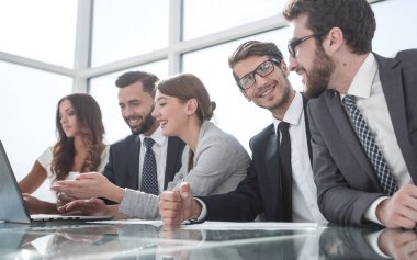 İş ekibi ofisteki masada oturuyor.