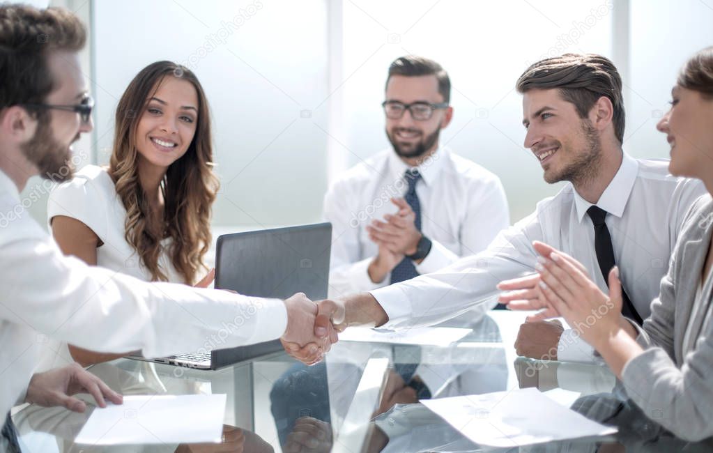 business partners shaking hands over the Desk.