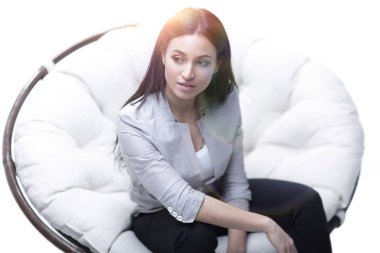 Genç kadın bir yuvarlak rahat yumuşak büyük sandalyede oturuyor.