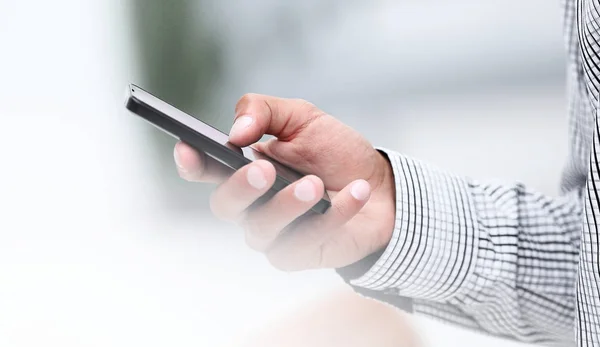 Primer plano. Un hombre sostiene un teléfono inteligente . — Foto de Stock