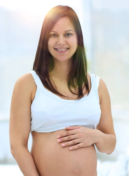 Portrait of young pregnant woman on a light background. — Stock Photo, Image