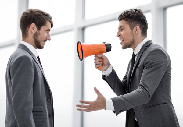 aggressive businessman with megaphone screaming on his coworker,