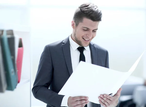 Lächelnder Geschäftsmann beim Lesen einiger Dokumente am Arbeitsplatz — Stockfoto