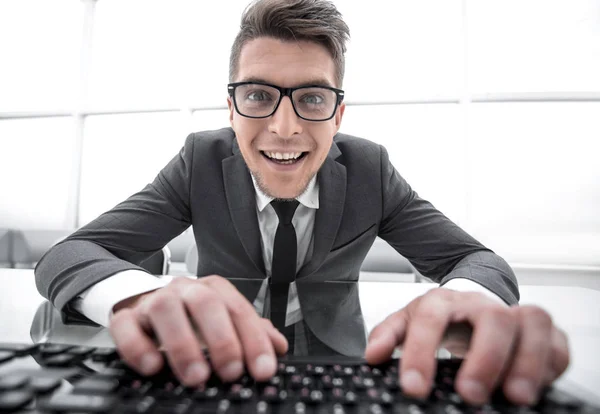 Joven sentado en el escritorio con las manos en el teclado y buscando clo — Foto de Stock