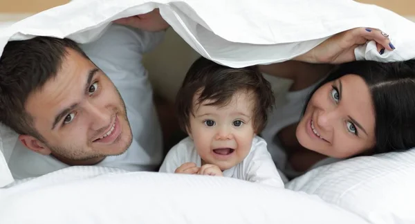 카메라 보면서 duvet 아래 포즈 행복 한 가족 — 스톡 사진