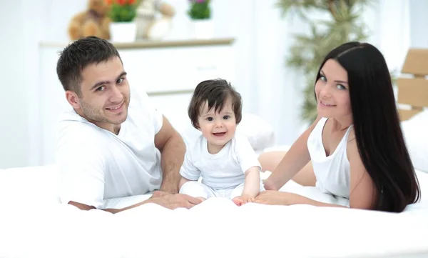 Une jeune famille avec de jeunes enfants au lit dans la chambre — Photo