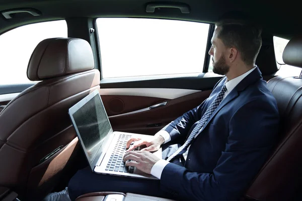 Επιχειρηματίας χρησιμοποιώντας ένα φορητό υπολογιστή στο πίσω κάθισμα ενός αυτοκινήτου — Φωτογραφία Αρχείου
