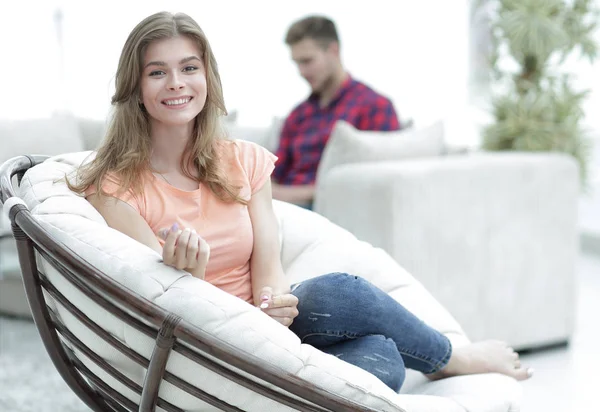 Smiling young woman sitting in a large comfortable chair — Stock Photo, Image
