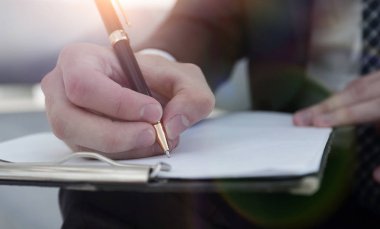 İşadamı bir sözleşme imzalar. Elinde kalem tutan.