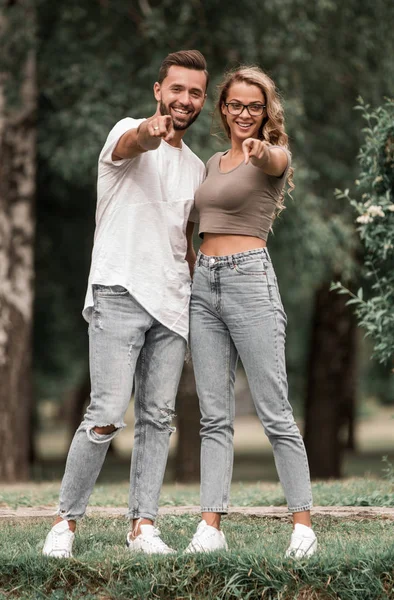 Älskande par stående i parken och pekar på dig — Stockfoto