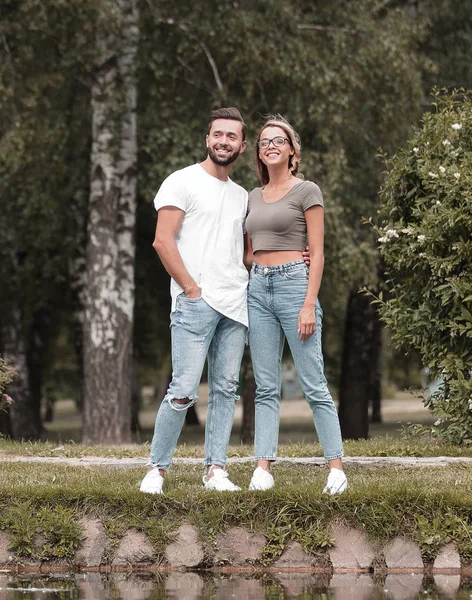 Par i kärlek står på gräset nära sjön — Stockfoto