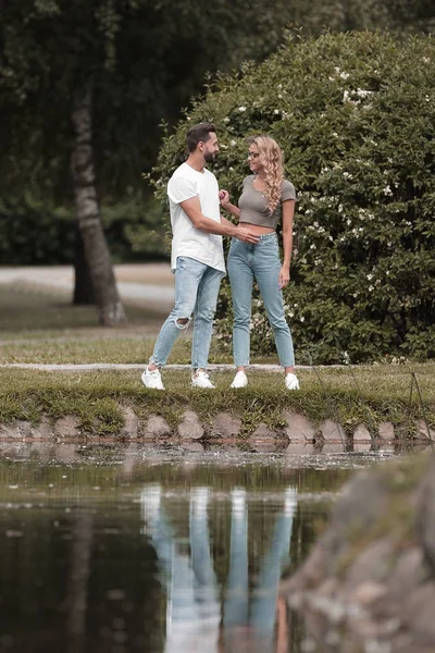 Älskande par stående nära en sjö i en stad Park — Stockfoto