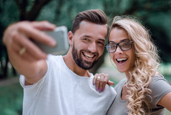 Stäng up.smiling ungt par tar selfie i city Park — Stockfoto